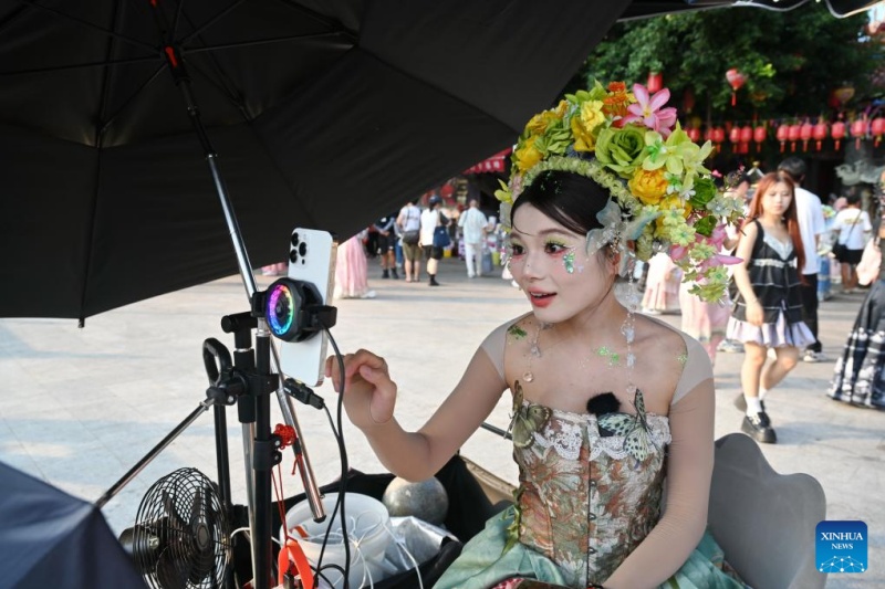 Une membre du personnel portant un couvre-chef fleuri présente des produits photographiques de voyage locaux via une diffusion en direct depuis le village de Xunpu, à Quanzhou, dans la province du Fujian (sud-est de la Chine), le 18 août 2025.(Lin Shanchuan/Xinhua)