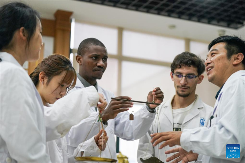 Pan Yinxing (1er à droite), maître de conférences à l'Université de médecine chinoise de l'Anhui, enseigne à des étudiants étrangers comment utiliser une balance traditionnelle à Hefei, capitale de la province de l'Anhui (est de la Chine), le 16 octobre 2025. (Photo/Xinhua)