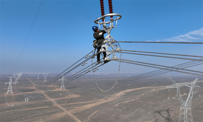 Xinjiang : des techniciens inspectent les lignes électriques en altitude pour éliminer les défauts à Qitai