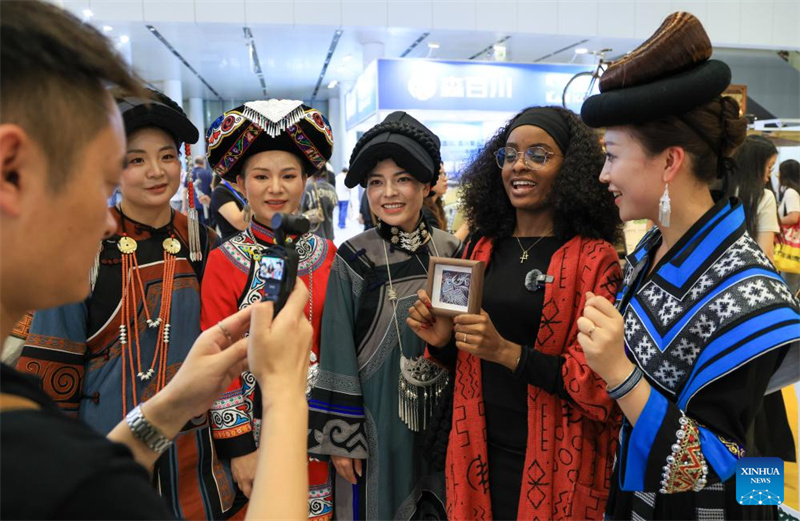 Un participant étranger échange avec des participants des groupes ethniques Miao et Yi lors du 22e Salon international des industries culturelles de Chine à Shenzhen, dans la province du Guangdong (sud de la Chine), le 21 mai 2026. (Mao Siqian/Xinhua)