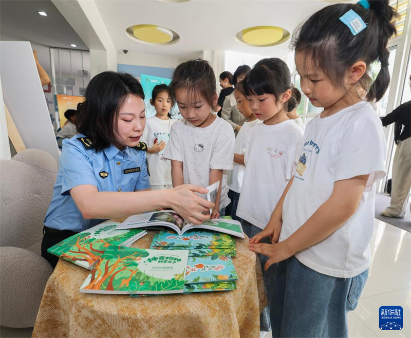 Des agents distribuent des brochures sur la biodiversité aux enfants du jardin d'enfants central du canton de Balidian à Huzhou, dans la province du Zhejiang (est de la Chine), le 21 mai 2026. (Xu Yu/Xinhua)