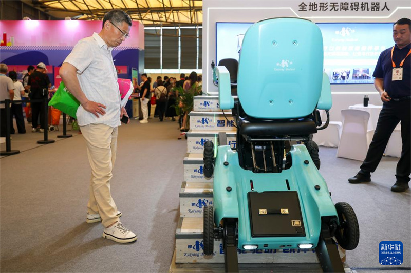 Des visiteurs regardent un robot tout-terrain capable montant des escaliers le 4 juin 2026. (Wang Xiang/Xinhua)