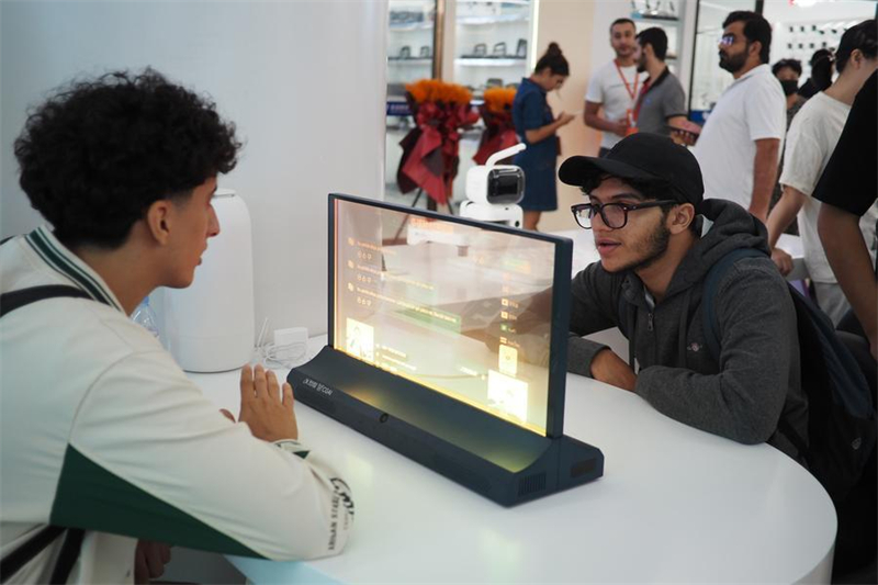 Des commerçants étrangers découvrent un dispositif interactif de traduction à intelligence artificielle au Centre mondial du commerce numérique de Yiwu, dans la province du Zhejiang (est de la Chine), le 14 octobre 2025.  (Liu Ziyi/Xinhua)