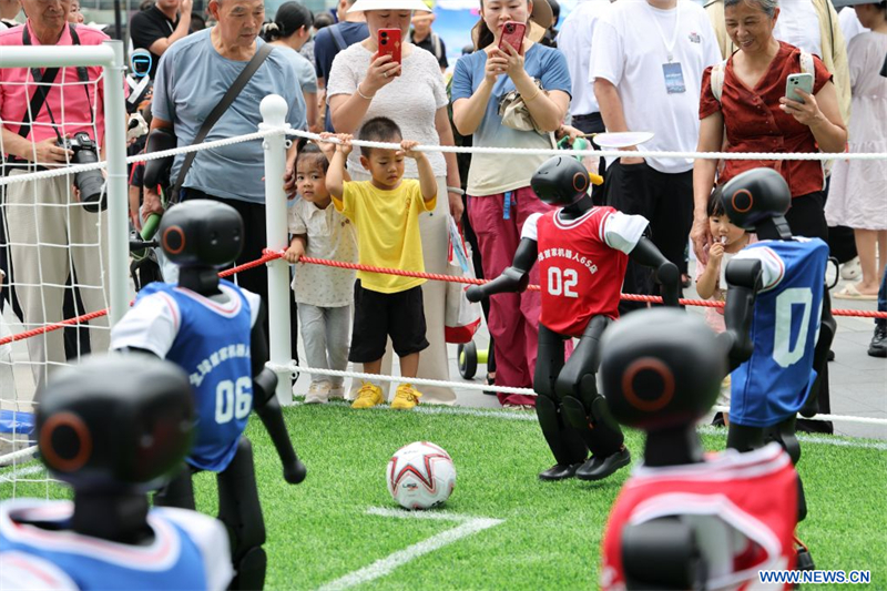 Des visiteurs regardent un match de foot joué par des robots dans le quartier des robots de l'arrondissement de Longgang, à Shenzhen, ville de la province chinoise du Guangdong (sud), le 25 juin 2026. (Photo : Liang Xu)