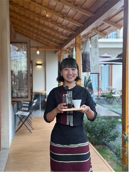 Zhao Hua et sa sœur tiennent un charmant café dans le comté de Menglian, dans la province du Yunnan (sud-ouest de la Chine), où elles vendent des grains de café provenant de leur propre ferme tout en préservant fièrement l'héritage culturel Wa. Les invités dégustant leur café peuvent regarder les femmes Wa démontrer les techniques traditionnelles de tissage du brocart transmises de génération en génération. (Hu Zunhui/Le Quotidien du Peuple en ligne)
