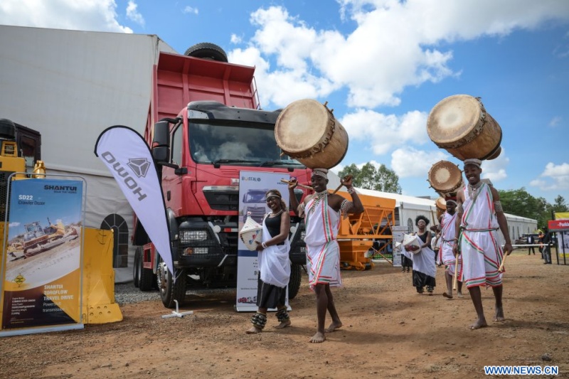 Des artistes en tenue traditionnelle passent devant le stand d'un exposant chinois de la 27e Buildexpo Kenya à Nairobi, au Kenya, le 8 juillet 2026. Des dizaines d'entreprises chinoises présentent leurs innovations à l'exposition, qui a ouvert ses portes mercredi dans la capitale kényane, Nairobi. (Xinhua/Yang Guang)