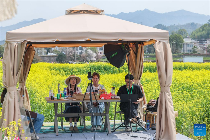 Des gens font la promotion de projets de tourisme culturel local près d'un champ de colza en fleurs à Jiande, dans la province du Zhejiang (est de la Chine), le 23 mars 2025. (Xu Yu/Xinhua)