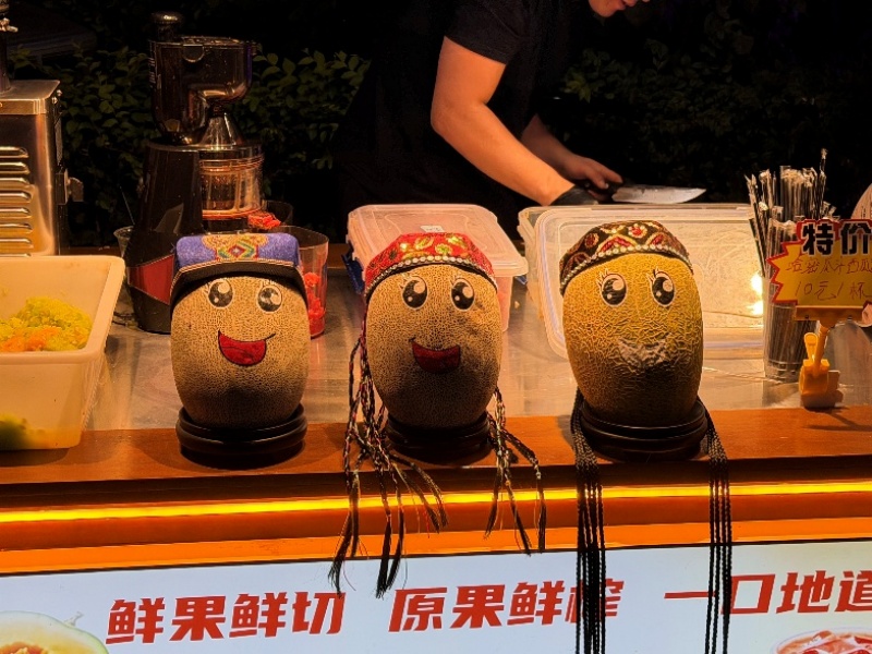 Un vendeur dessine des visages sur ses melons de Hami dans la rue ancienne d'Altun à Hami, dans la région autonome ouïgoure du Xinjiang, (nord-ouest de la Chine). (Le Quotidien du Peuple en ligne /Michael Kurtagh)
