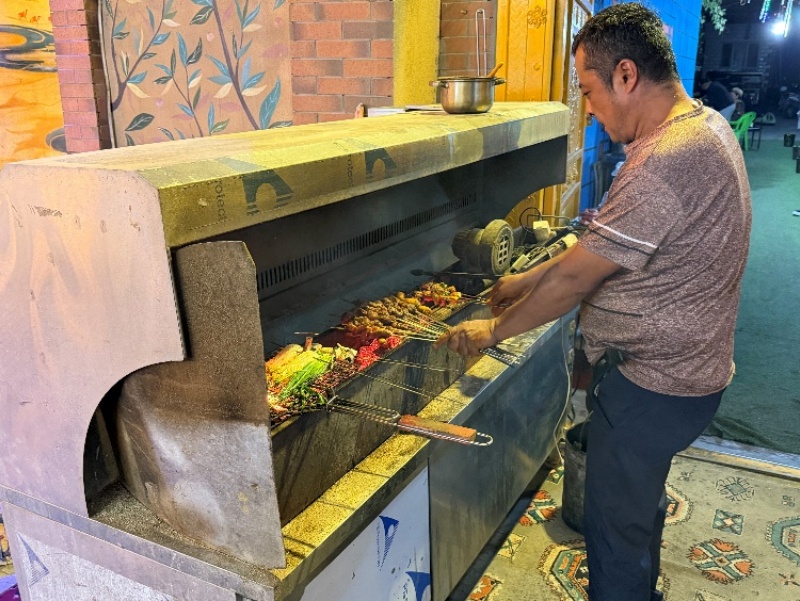 Un homme fait griller des brochettes dans la rue ancienne d'Altun à Hami, dans la région autonome ouïgoure du Xinjiang (nord-ouest de la Chine). (Michael Kurtagh/Le Quotidien du Peuple en ligne)