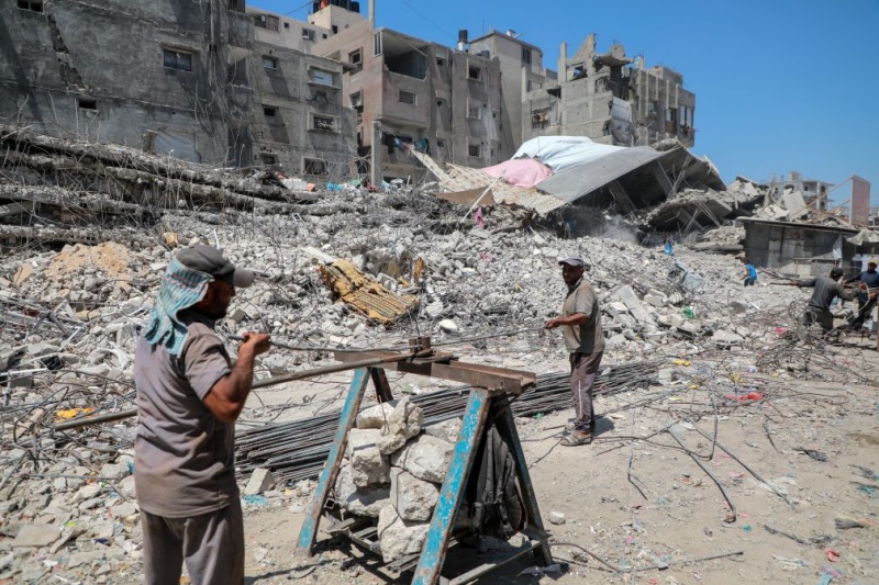 Des Palestiniens récupèrent des barres de fer dans les décombres de maisons détruites à Gaza, le 18 août 2026, alors que la bande de Gaza connaît une pénurie de matériaux de construction. (Xinhua/Rizek Abdeljawad)