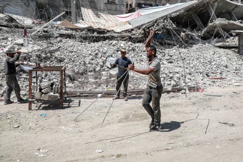 Des Palestiniens récupèrent des barres de fer dans les décombres de maisons détruites à Gaza, le 18 août 2026, alors que la bande de Gaza connaît une pénurie de matériaux de construction. (Xinhua/Rizek Abdeljawad)