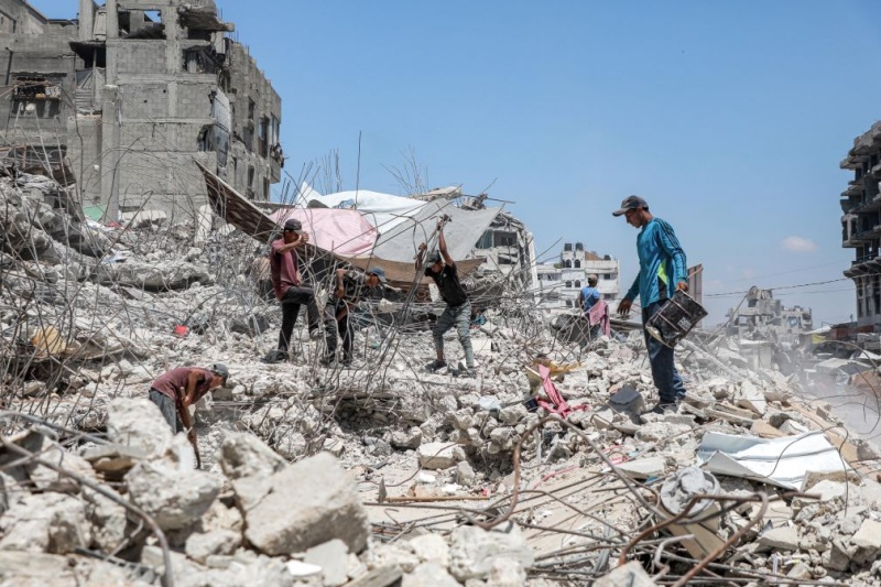 Des Palestiniens récupèrent des barres de fer dans les décombres de maisons détruites à Gaza, le 18 août 2026, alors que la bande de Gaza connaît une pénurie de matériaux de construction. (Xinhua/Rizek Abdeljawad)