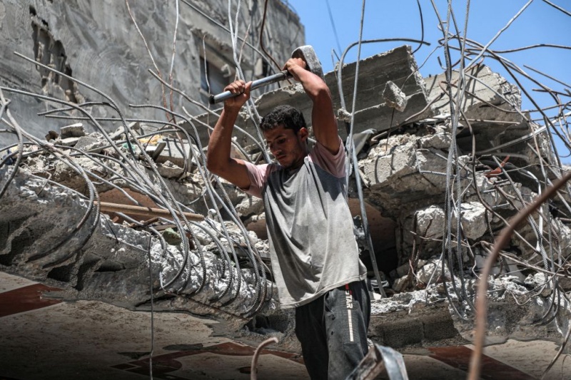 Un Palestinien récupère des barres de fer dans les décombres de maisons détruites à Gaza, le 18 août 2026, alors que la bande de Gaza connaît une pénurie de matériaux de construction. (Xinhua/Rizek Abdeljawad)