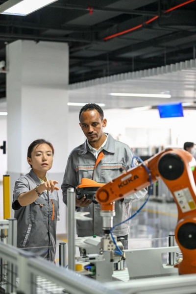 L'Ethiopien Tola Tsegaye Alemu (à droite) fait tourner un robot industriel sous la direction d'une enseignante de l'Université de technologie et d'éducation de Tianjin, à Tianjin, dans le nord de la Chine, le 27 juin 2024. (Xinhua/Sun Fanyue)