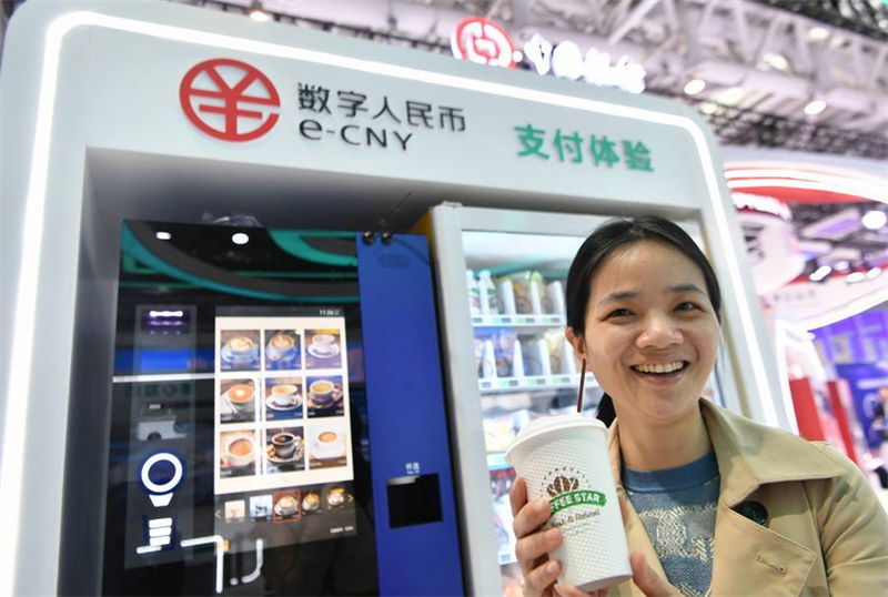 Une visiteuse présente une tasse de café achetée grâce au yuan numérique chinois (e-CNY), lors d'une exposition organisée dans le cadre du 6e sommet Digital China (« Chine Numérique ») à Fuzhou, capitale de la province du Fujian (sud-est de la Chine), le 26 avril 2023. (Wei Peiquan/Xinhua)
