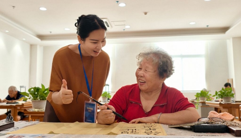 Photo d'archives non datée montrant Liang Yinxia aidant une personne âgée à s'exercer à la calligraphie au centre de soins Wuxiang de Nanning, capitale de la région autonome Zhuang du Guangxi (sud de la Chine).