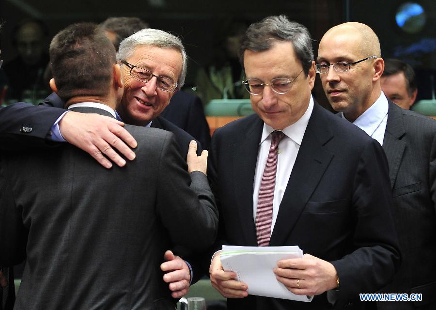 Le Premier ministre du Luxembourg et président de l'Eurogroupe Jean-Claude Juncker (2e à gauche) embrasse le ministre grec des Finances Yannis Stournaras (1er à gauche) à côté du président de la Banque centrale européenne Mario Draghi (2e à droite) avant une réunion de l'Eurogroupe au siège de l'UE, à Bruxelles, capitale de la Belgique, le 12 novembre 2012. Les ministres des Finances de la zone euro se sont réunis lundi pour discuter de la situation de la dette en Grèce. 