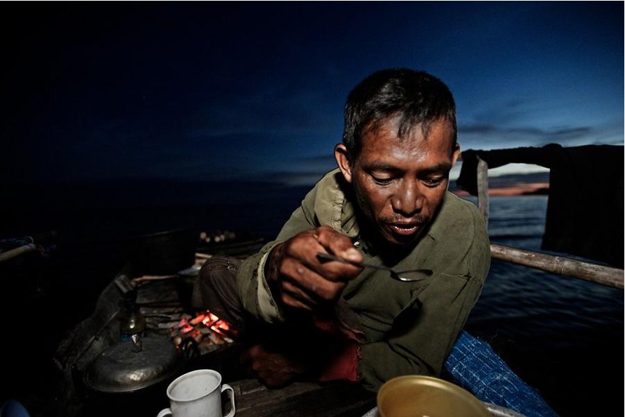 Un homme prend son dîner à bord de son bateau.