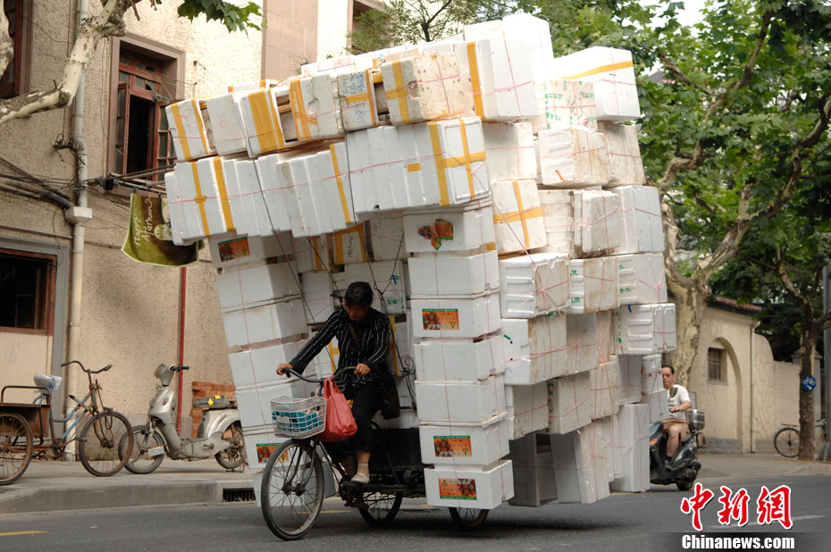A Shanghai, en Chine, une femme transporte des déchets de mousse (plus de cents caisses d'emballage) et ce sur une toute petite tricyclette.