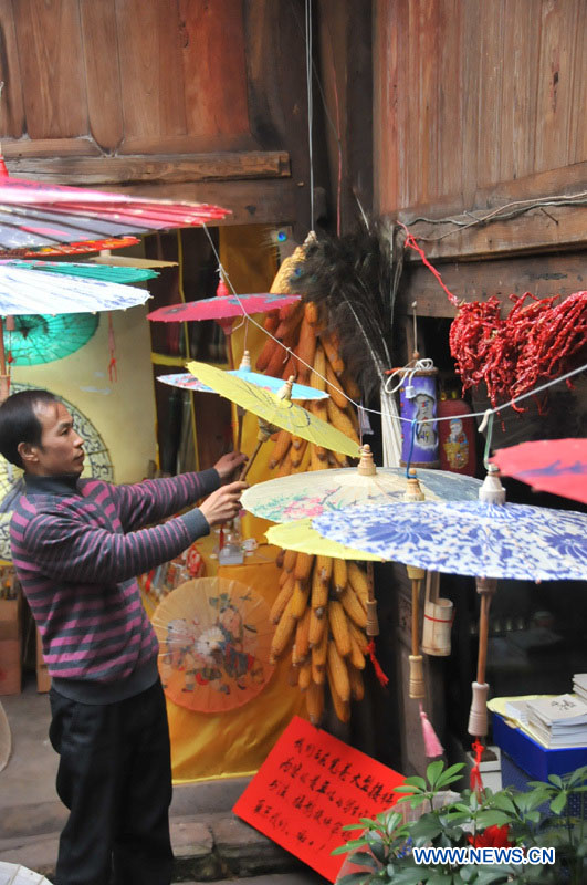 Un artisan regarde des parapluies de papier huilé dans un atelier du district de Xixiu, à Anshun, ville de la province du Guizhou (sud-ouest), le 12 novembre 2012. Fabriqué en papier huilé et doté d'une armature en bambou, ce type de parapluie est un objet artisanal traditionnel chinois. Les techniques de fabrication du parapluie de papier huilé ont été introduites au Guizhou durant la dynastie Ming. (Photo : Huang Yong)
