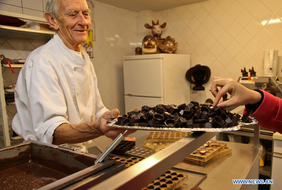 Un employé (à gauche) invite un visiteur à goûter des chocolats au Musée du cacao et du chocolat de Bruxelles, à l'occasion de la semaine du chocolat organisée dans la capitale belge, le 21 novembre 2012. (Photo : Yan Ting)