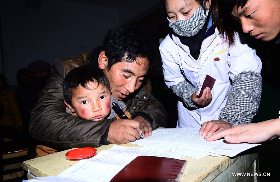 Chagba (deuxième à gauche), père de Luozhou Jigme, un garçon souffrant d'une maladie cardiaque congénitale, signe le formulaire de consentement pour une opération, dans le district de Nangqian de la province du Qinghai (nord-ouest), le 3 décembre 2012.