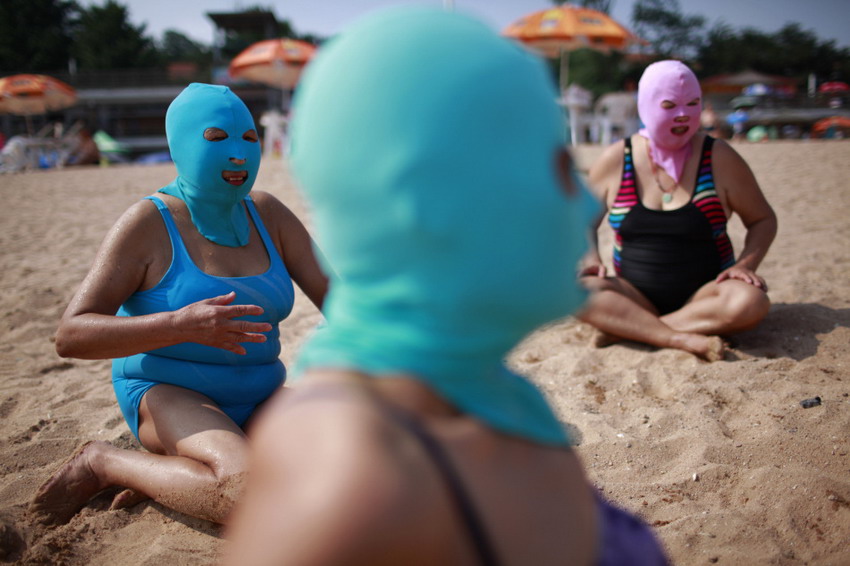 Le 6 juillet 2012 à Qingdao dans la province chinoise du Shandong, des femmes portant des cagoules en nylon se reposent sur la plage. Ce genre de masque a été inventé il y a 7 ans, dans le but de protéger le visage contre les rayons du soleil nuisibles. REUTERS/Aly Song