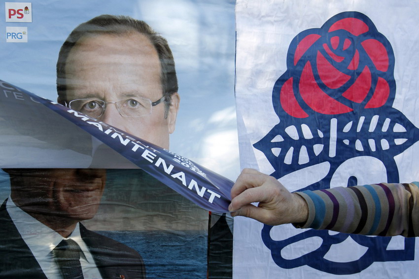Le 12 avril 2012, un partisan du parti socialiste colle une affiche de leur candidat François Hollande sur celle du président Nicolas Sarkozy. REUTERS/Stephane Mahe