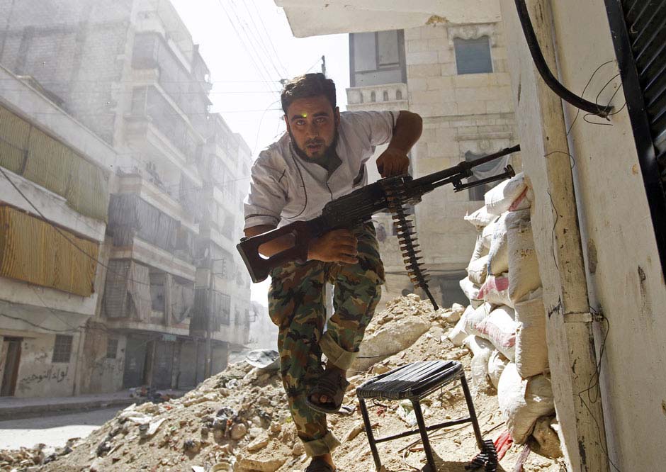 Le 7 août 2012 dans une rue de la ville d'Alep en Syrie, un combattant de l'Armée libre syrienne cherche un abri pendant un accrochage avec l'Armée gouvernementale du pays. REUTERS / Goran Tomasevic