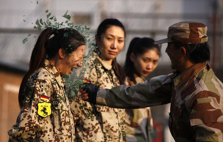 Le 13 janvier 2012 à Beijing en Chine, un instructeur pour la formation des gardes de sécurité casse une bouteille en verre sur la tête d'une élève pendant un cours. REUTERS/David Gray