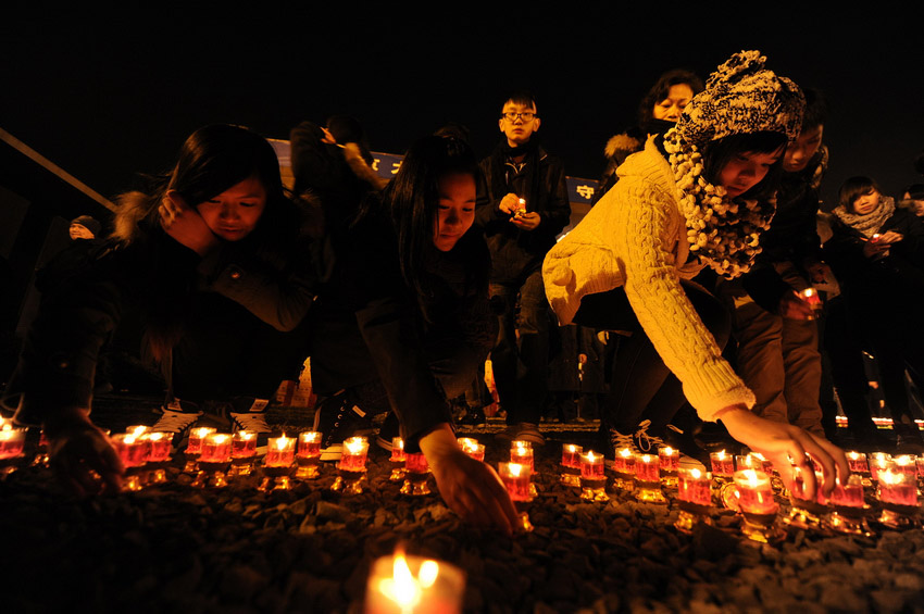 Les 12 décembre sur la place commémorative du Mémorial du massacre de Nanjing, des représentants des étudiants de Hong Kong allument des bougies qu' ils déposent sur le sol. (Xinhua / Han Yuqing)