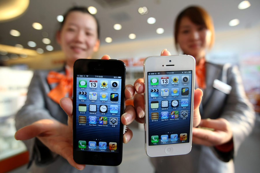 Deux employées de la société chinoise de télécommunications China Unicom à Wuxi montrent les iPhones 5 nouvellement arrivées, le 13 décembre 2012. L'Apple lance l'iPhone 5 en Chine continentale aujourd'hui.