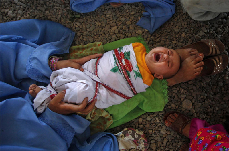 Une Afghane tient son fils en attendant de retourner en Afghanistan depuis un centre de rapatriement financé par les Nations Unies, à l'ouest de Peshawar, le 31 mai 2012.