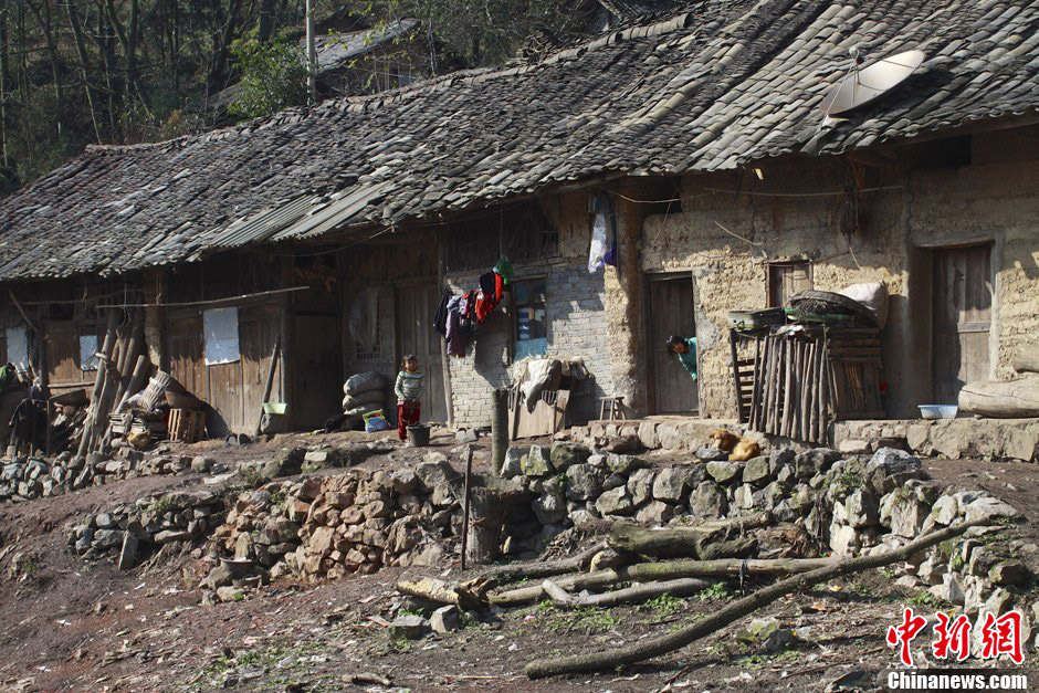 Dans le village Laodong, presque toutes les familles habitent dans les maisons en terre comme celle sur la photo. Deux enfants regardent des inconnus devant leur maison. Leur parents sont allés travailler dans la ville. (Chinanews/Feng Zhonghao)