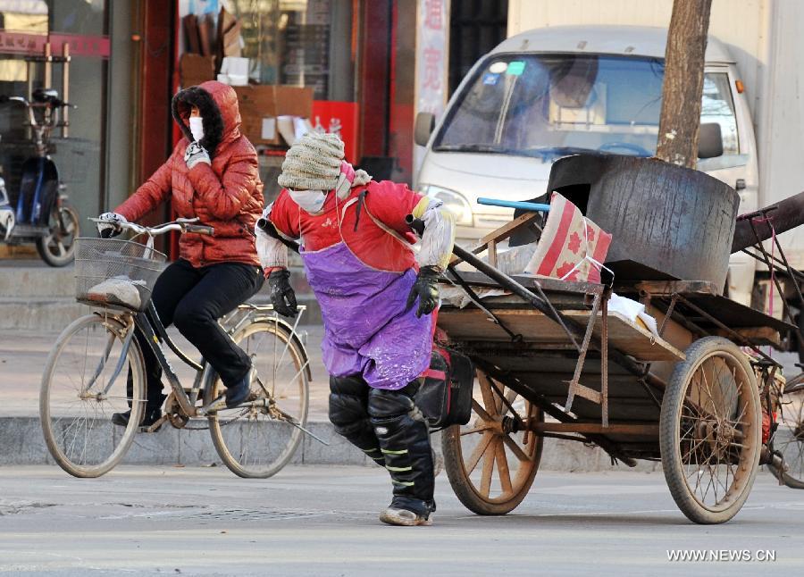 Une femme tire une charrette à bras dans le vent froid à Baoding, dans la province du Hebei (nord), le 23 décembre 2012. Le centre météorologique de la province a émis une alerte bleue au froid samedi. La plupart du Hebei a souffert d'une chute brutale des températures et de grands vents.