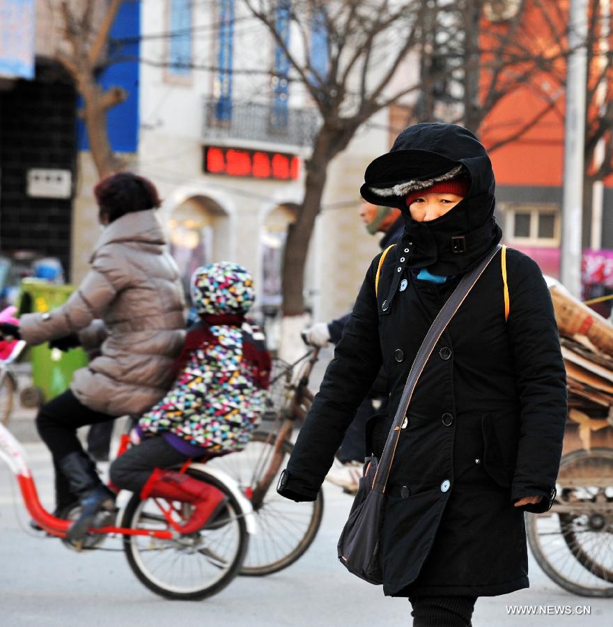 Une habitante locale marche dans le vent froid à Baoding, dans la province du Hebei (nord), le 23 décembre 2012. Le centre météorologique de la province a émis une alerte bleue au froid samedi. La plupart du Hebei a souffert d'une chute brutale des températures et de grands vents.