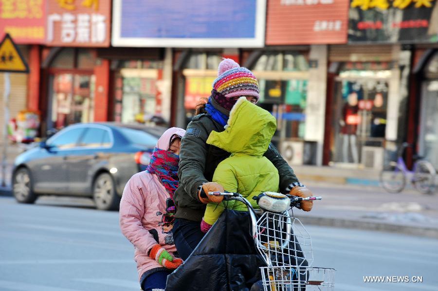 Une famille roule dans le vent froid à Baoding, dans la province du Hebei (nord), le 23 décembre 2012. Le centre météorologique de la province a émis une alerte bleue au froid samedi. La plupart du Hebei a souffert d'une chute brutale des températures et de grands vents.