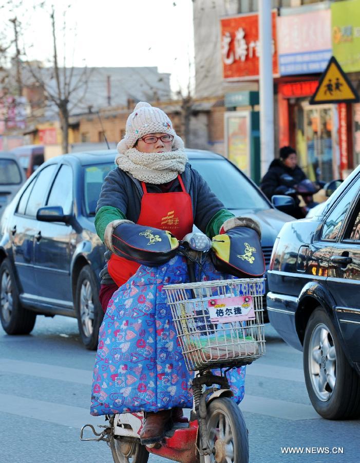Une habitante locale roule dans le vent froid à Baoding, dans la province du Hebei (nord), le 23 décembre 2012. Le centre météorologique de la province a émis une alerte bleue au froid samedi. La plupart du Hebei a souffert d'une chute brutale des températures et de grands vents.