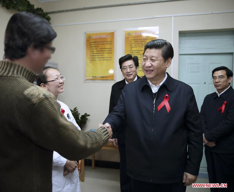 Photo d'archive prise en novembre 2012 montrant Xi Jinping serrant la main à un séropositif alors qu'il participait aux activités de la Journée mondiale contre le sida au Centre de santé du quartier Puhuangyu dans l'arrondissement de Fengtai à Beijing, en Chine.