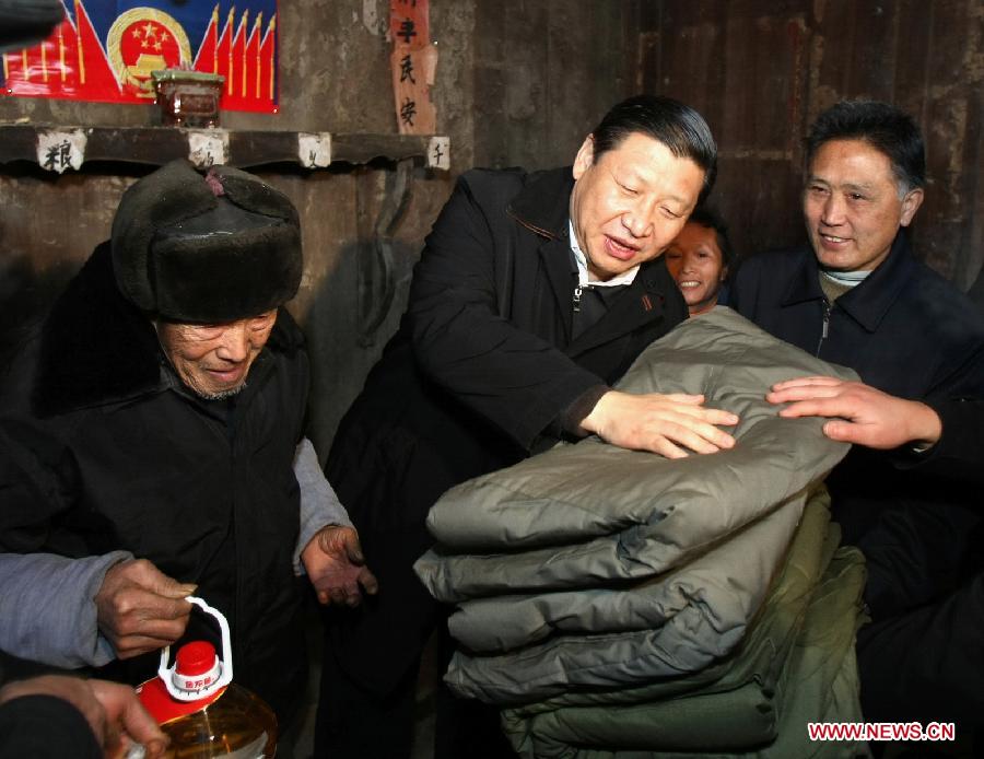 Photo d'archive prise en janvier 2008 montrant Xi Jinping (au centre) rendant visite à Tang Zhaowei, un villageois du groupe ethnique Dong qui a subi une perte familiale en raison de la neige et des tempêtes de verglas, dans le village de Laoshankou du bourg de Gaolouping, dans la province du Guizhou (sud-ouest), en Chine.