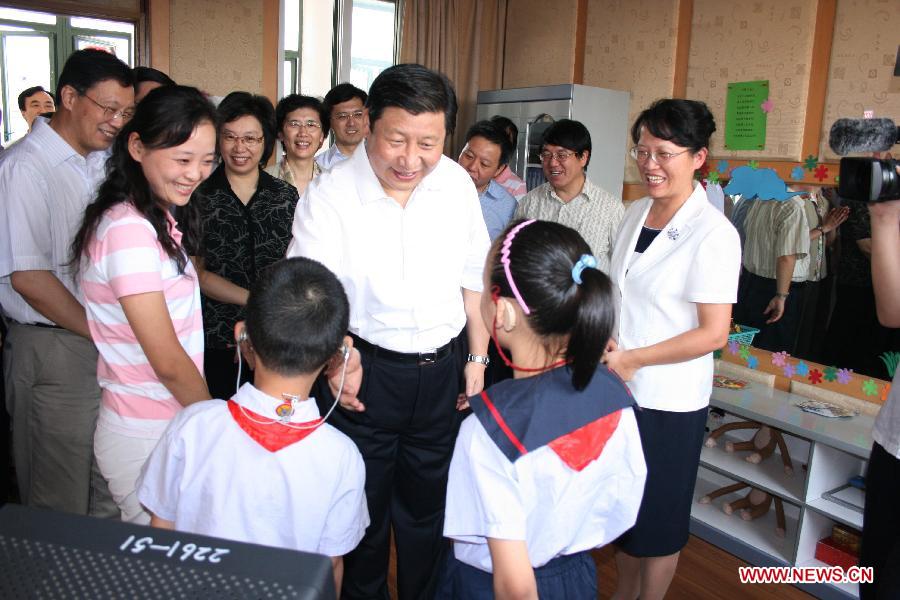 Photo d'archive prise en septembre 2007 montrant Xi Jinping (au centre), alors qu'il était secrétaire du Comité du Parti communiste chinois (PCC) pour la municipalité de Shanghai, parlant avec des élèves malentandants à l'école Qiyin dans l'arrondissement de Minhang à Shanghai (est), en Chine.