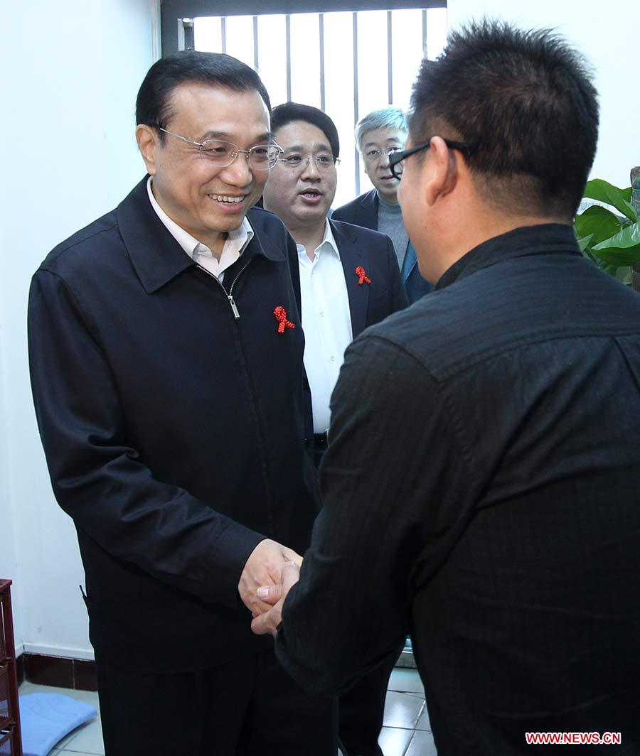 Photo d'archive prise le 18 novembre 2011 montrant Li Keqiang (à gauche) serrant la main à un séropositif lors de son étude sur la prévention du sida à Beijing, en Chine.