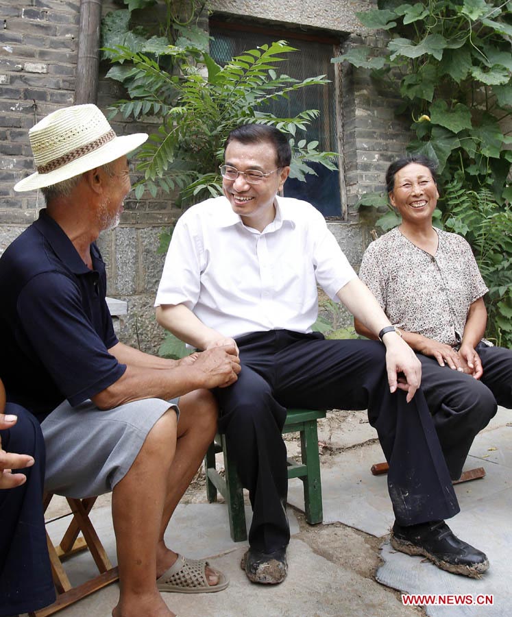 Photo d'archive prise le 8 juillet 2010 montrant Li Keqiang (au centre) parlant avec le villageois pauvre Sun Shujie et sa femme dans le village de Dasun du district de Jiaxiang de la ville de Jining dans la province du Shandong (est), en Chine.