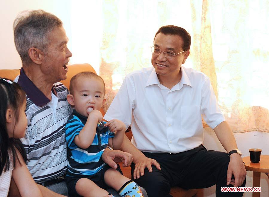 Photo prise en août 2011 montrant Li Keqiang (1er à droite) rendant visite à des habitants de logements sociaux lors de sa visite à Hong Kong, en Chine.　