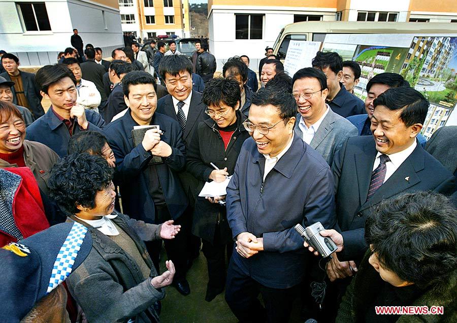 Photo d'archive prise le 3 novembre 2005 montrant Li Keqiang parlant avec des gens qui ont emménagé dans de nouveaux logements grâce à la réhabilitation des bidonvilles à Fushun, dans la province du Liaoning (nord-est), en Chine.