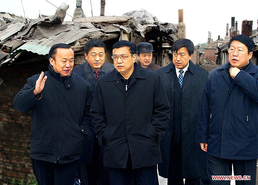 Photo d'archive prise le 26 décembre 2004 montrant Li Keqiang (2e à gauche), alors qu'il était secrétaire du Comité du Parti communiste chinois (PCC) pour la province du Liaoning, s'engageant à résoudre les problèmes de logement du peuple lors de son inspection dans un bidonville à Fushun, dans la province du Liaoning (nord-est), en Chine.　　