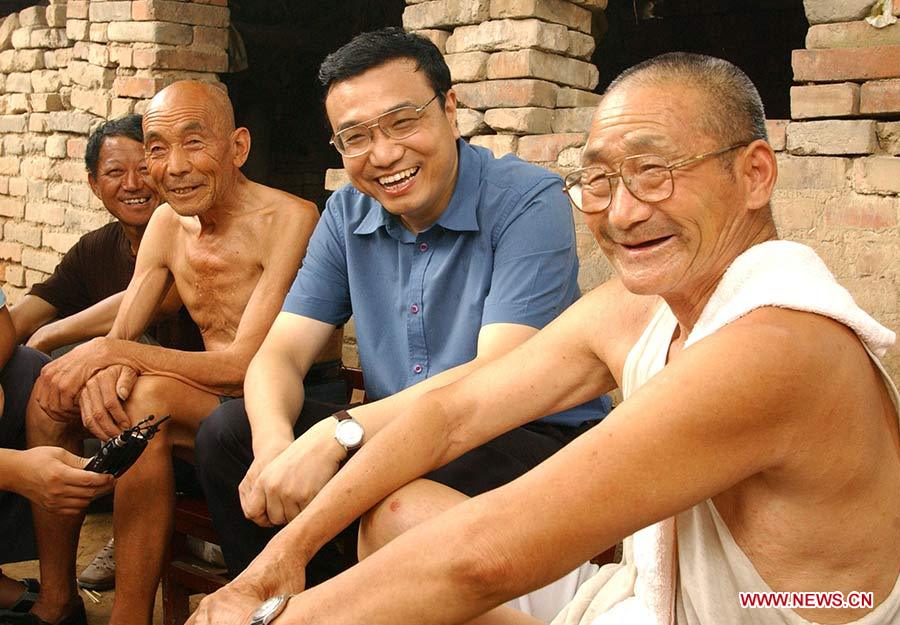 Photo d'archive prise le 8 août 2003 montrant Li Keqiang (2e à droite), alors qu'il était secrétaire du Comité du Parti communiste chinois (PCC) pour la province du Henan, parlant avec des villageois du village de Mazhuang dans le bourg de Qiaobei du district de Yuanyang au cours de son étude dans la campagne du Henan, dans le centre de la Chine.