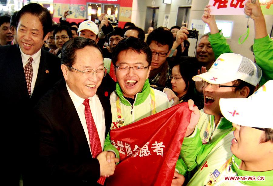 Photo d'archive prise le 31 octobre 2010 montrant Yu Zhengsheng (2e à gauche au premier plan) rendant visite à des volontaires travaillant à l'Exposition universelle de Shanghai.