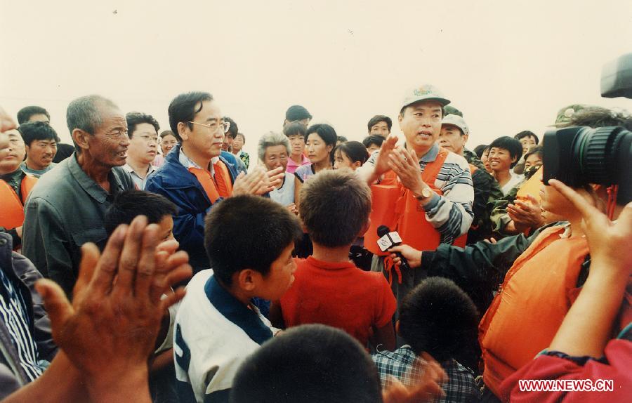 Photo d'archive prise le 20 août 1998 montrant Zhang Dejiang (à droite) rendant visite aux victimes des inondations afin de diriger les opération de secours dans le bourg de Gashigen dans le district de Zhenlai de la province du Jilin (nord-est), en Chine.