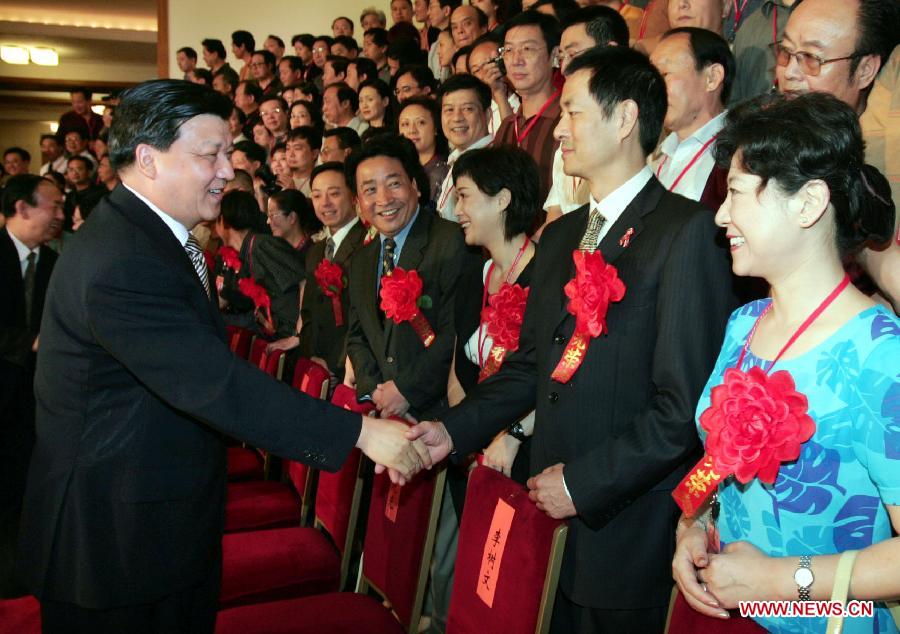 Photo d'archive prise le 19 juillet 2004 montrant Liu Yunshan (à gauche au premier plan), rencontrant les représentants participant à une cérémonie de félicitation pour les artistes et littéraires chinois jeunes et d'âge moyen ayant fait preuve de vertu suprême ou de grande réalisation artistique au Grand Palais du Peuple à Beijing, en Chine. (Photo : Li Xueren)